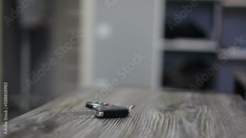 The male driver takes the keys to the ignition of the car from the table and turns off the light in the room as he leaves.