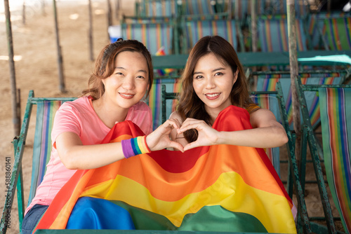 Lesbian woman with gay pride rainbow flag making a heart shape, a symbol of the LGBT community, equal rights, beauty and love