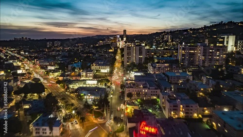 Forwards fly above busy streets of West Hollywood. Hyper lapse footage of city at dusk. Los Angeles, California, USA