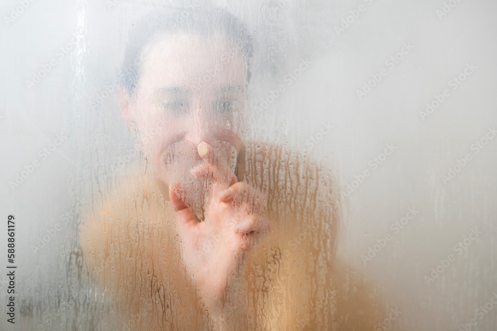 girl showering. girl drawing a heart on the misted shower glass