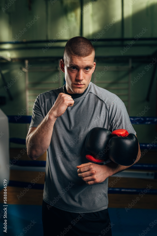 Portrait of a Caucasian man fighter looking at the camera with his fist up and holding gloves Portrait of a Caucasian man fighter looking at the camera with his fist up and holding gloves