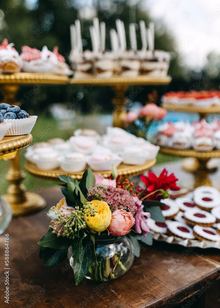 Candy bar at a party. Bouquet of yellow roses on a table with different handmade desserts.