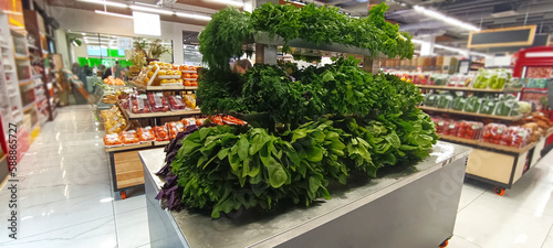 fresh greenery on iron shelf in supermarket showcase. GROCERY SHOP SELLING fresh spinach  green grass and other VEGETABLES