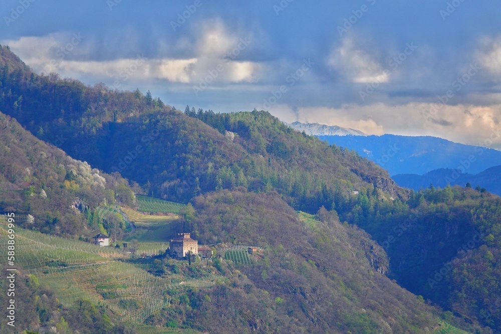 Fototapeta premium Blick über eine Landschaft in Südtirol bei Meran mit einer kleinen Burg umrahmt von Wäldern