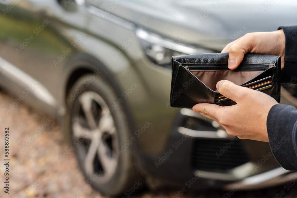Person holding an empty wallet in the hands stands front car. Insurance, loan and buying car finance concept