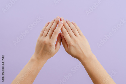 Woman's hands on lilac background. Skin care for hands, manicure and beauty treatment.
