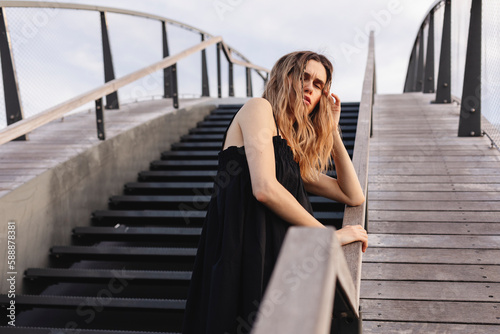 Close up depression blonde woman with two thin braids standing on the stairs. Depression, sadness, problem concept. Unhappy upset woman touching temples, suffering from strong tension headache.