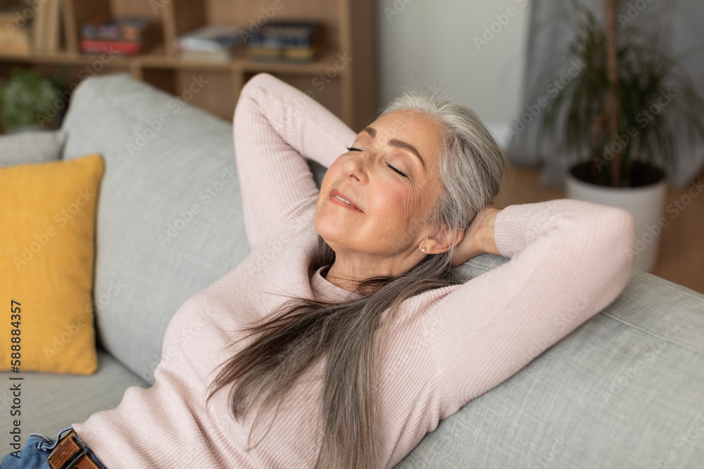 Happy glad pretty caucasian senior female with closed eyes sleep, enjoys leisure time, lies on sofa in living room Happy glad pretty caucasian senior female with closed eyes sleep, enjoys leisure time, lies on sofa in living room