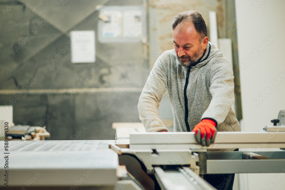 A dedicated worker is operating cutting machine at his workshop. A dedicated worker is operating cutting machine at his workshop.