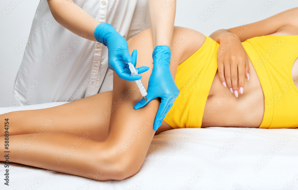 Fototapeta premium beautician makes lipolytic injections to burn fat on woman's belly, legs and waist. Women's aesthetic cosmetology in a beauty salon. The concept of cosmetology.
