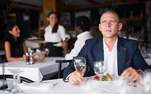 adult man thinking and eating in modern cafe