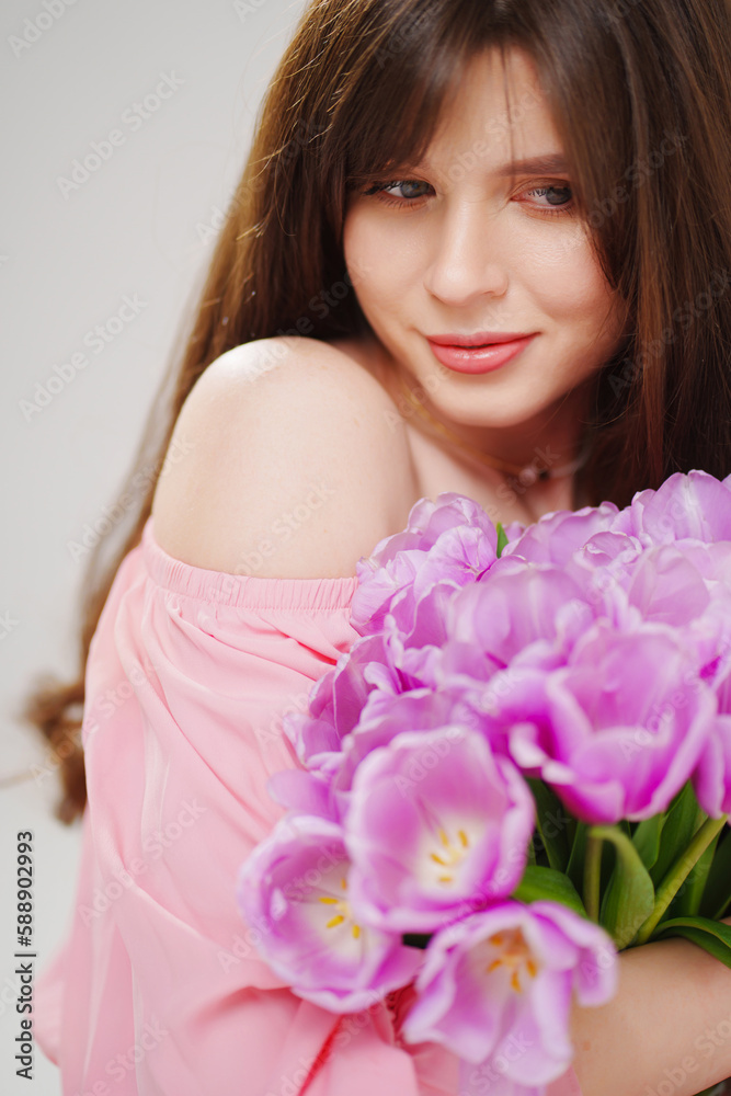 beautiful young brunette woman with long hair in pink with a bouquet of tulips. beautiful young brunette woman with long hair in pink with a bouquet of tulips.