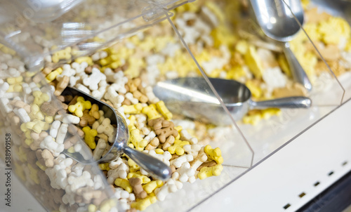 Pet shop display shelf with containers full of nutritious snacks for dogs in form of colorful small bones