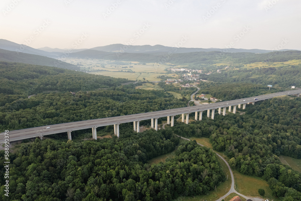Transport bridge in mountainous area, road and trees. Light fog in the mountains. Development of transport systems. A panoramic view of nature from above.