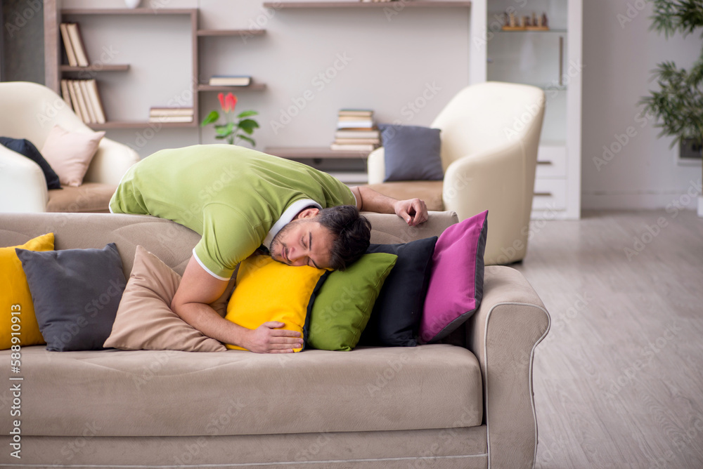 Young man with a lot of pillows sitting on the sofa Young man with a lot of pillows sitting on the sofa
