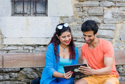 mixed race couple together in Villanueva Asturias using tablet technology outdoors on holyday photo
