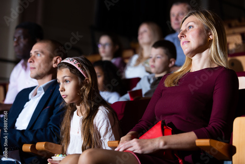 mother, father and their children sitting at film in auditorium photo