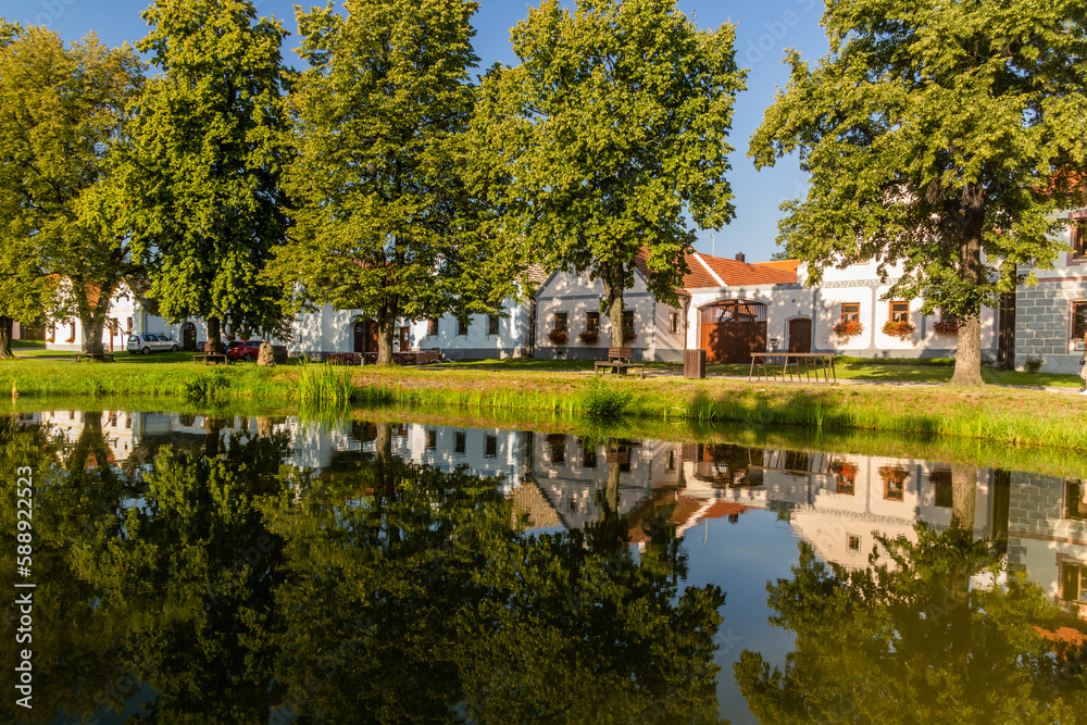 Pond and traditional houses of rural baroque style in Holasovice village, Czech Republic