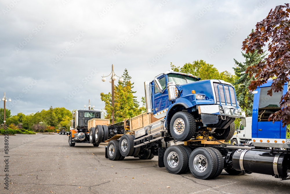 Blue big rig day cab semi truck towing another semi trucks coupled to each other with the fifth wheel saddle Blue big rig day cab semi truck towing another semi trucks coupled to each other with the fifth wheel saddle