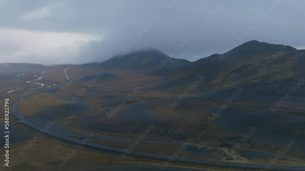 Aerial view of a road crossing a valley with mountain landscape at sunset in Highlands region of Iceland.