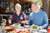 Positive adult couple enjoying lunch on outdoor terrace of country restaurant..