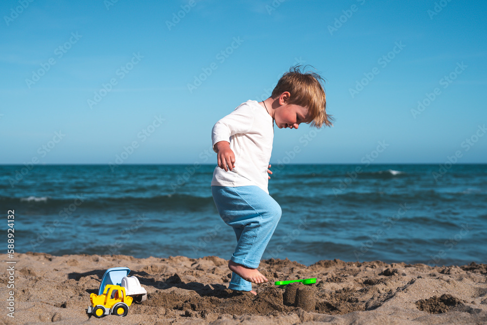 little boy 3 years old plays in the sand on the beach with toys little boy 3 years old plays in the sand on the beach with toys