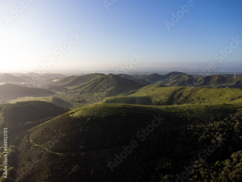 Aerial view of beautiful forest full of nature and pasture fields in Trememb   in Vale da Para  ba in S  o Paulo. Mountains and hills in sunny day. Lots of green and tropical vegetation. Drone. Sunset