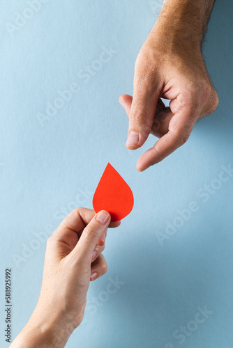Foto Hands of caucasian woman passing blood drop to caucasian man, on blue background