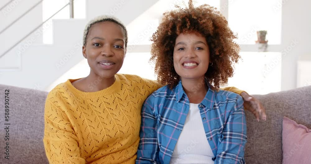 Portrait of happy diverse female lesbian couple having video call in living room in slow motion Portrait of happy diverse female lesbian couple having video call in living room in slow motion