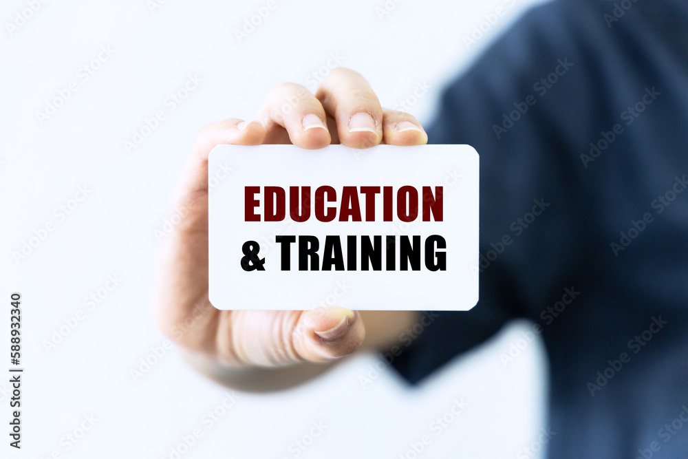Education and training text on blank business card being held by a woman's hand with blurred background. Business concept about education. Education and training text on blank business card being held by a woman's hand with blurred background. Business concept about education.