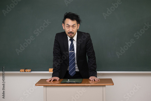教壇の黒板の前に立つ男性教師