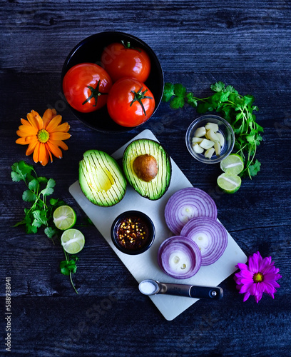 Food, Preparing fresh avocado and ingredients for Guacamole, top down view veggies on dark driftwood background countertop