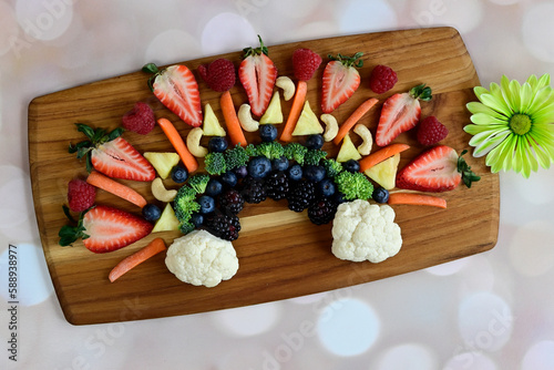 Fresh fruit and veggies arranged on butcher block, top down view berries and vegetables in a rainbow shape