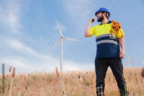 Winmill engineer or sustainable power technician working and talking by walkie-talkie for repair the turbine and the generator. front view of professional of renewable energy. High quality photo photo