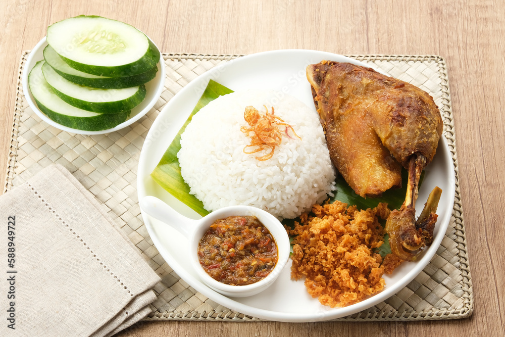 Bebek Goreng Kremes, served with chili sauce (sambal) and cucumber. Indonesian food
