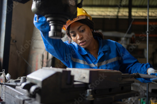 African black woman wearing blue safety uniform working control with heavy machine in factory