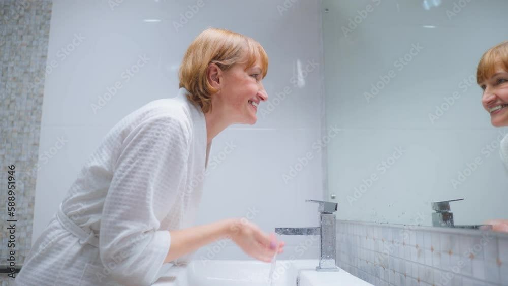 Caucasian senior woman wash and clean face with facial foam and water.
