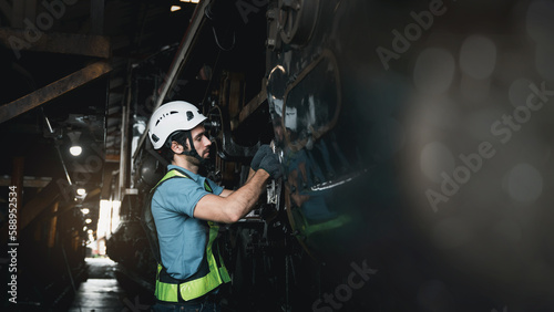 Engineer are working in the factory. Worker helping to repair and inspect the machine's readiness. Mechanical technicians are maintaining the engine in the train garage that is malfunctioning.