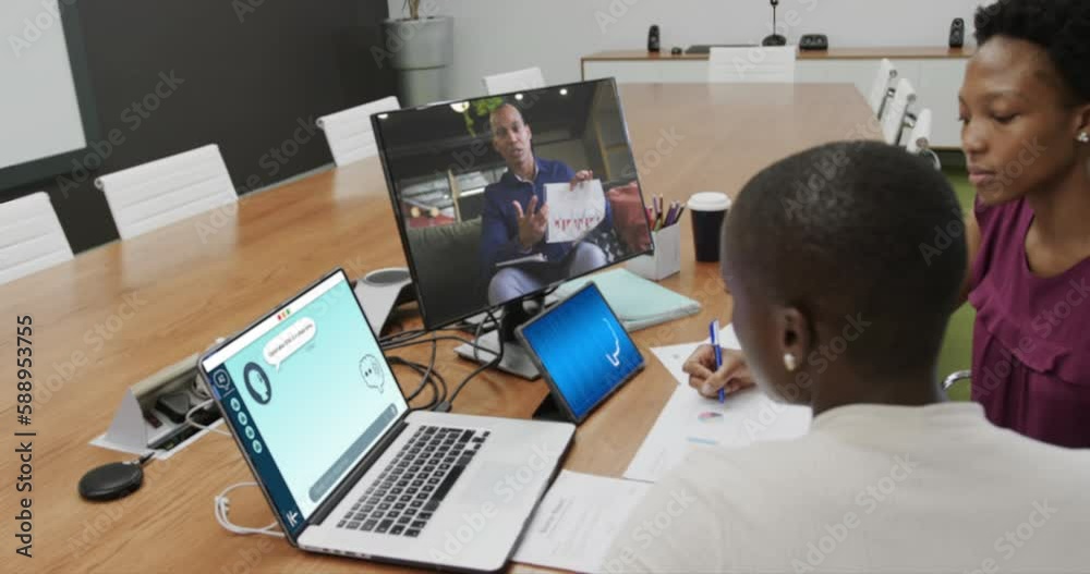 Diverse businesswomen in office using computer with video call and ai messaging on screens