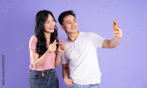 image of asian couple holding smartphone, isolated on purple background