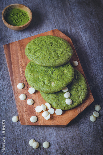 Matcha cookies with macadamia nuts and white chocolate chips on a dark wooden table