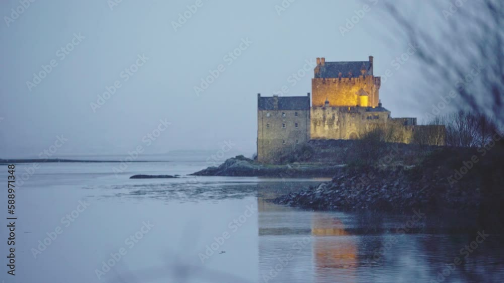 Camera focuses on the Eilean Donan Castle through snowfall on a cold evening. Scotland views and castles. Camera focuses on the Eilean Donan Castle through snowfall on a cold evening. Scotland views and castles.