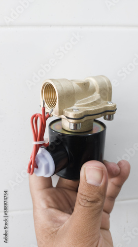 Holding the Solenoid Valve with brass body and power input  220 VAC ,for  operating water control  supply. photo