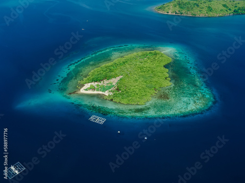 Aerial view with island in tropics and ocean with coral reef.