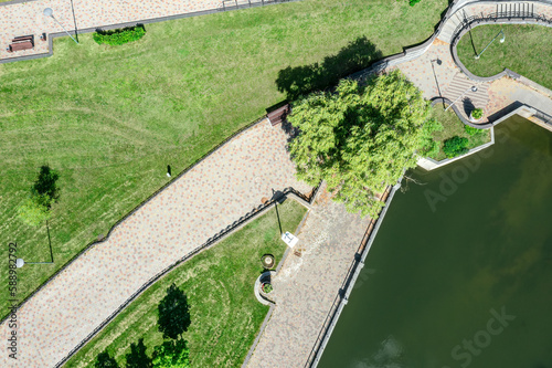 walking paths on riverbank in summer city park. bright sunny day. aerial photography with drone.