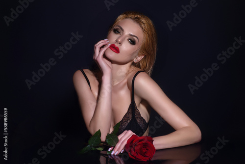 Sexy woman with red rose. Slim sexy beautiful woman with naked shoulder hold red roses, isolated on studio background. Portrait of sensual girl with flowers. © Volodymyr