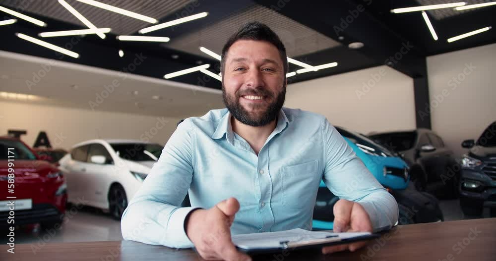 Portrait of young car salesman at dealership salon, looking at camera with tablet in hands Portrait of young car salesman at dealership salon, looking at camera with tablet in hands