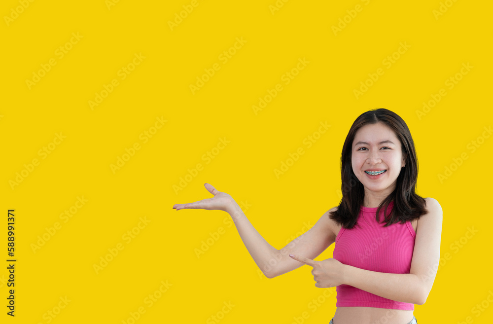 Asian woman with holding copyspace imaginary on the palm to insert an ad, Showing copyspace pointing, Showing her hand to present something on yellow background. Asian woman with holding copyspace imaginary on the palm to insert an ad, Showing copyspace pointing, Showing her hand to present something on yellow background.