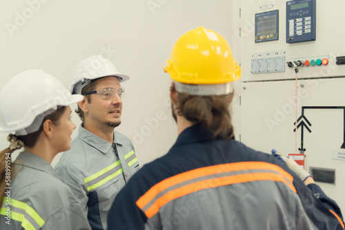 Electric power engineering team inspecting system of a large solar energy storage station in the middle of the field of solar cells on an area of hundreds of acres