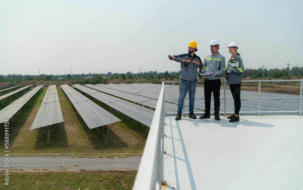 On the rooftop of a large solar energy storage station building A team of electric power engineers inspecting solar panels that have been installed on hundreds of acres of fields. On the rooftop of a large solar energy storage station building A team of electric power engineers inspecting solar panels that have been installed on hundreds of acres of fields.